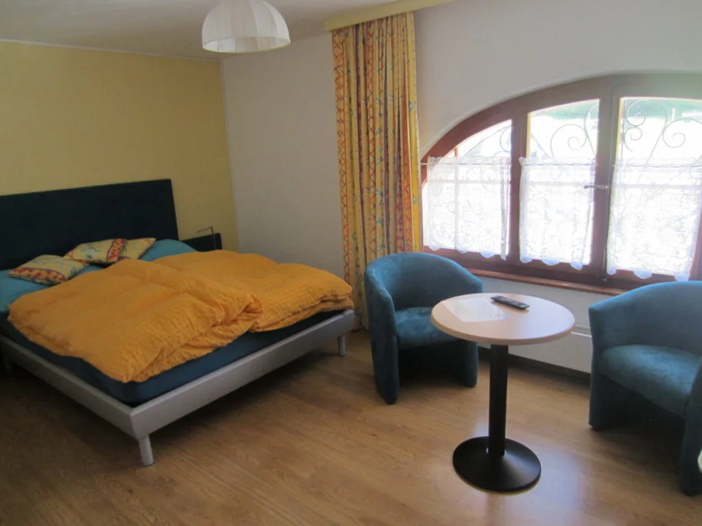 Chambre double avec fauteuils et grande fenêtre au restaurant Les Cluds.