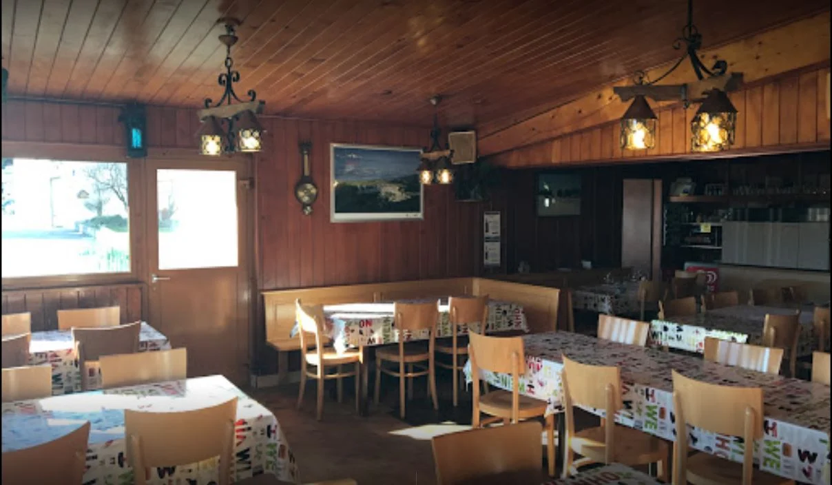 La salle du restaurant Les Cluds, avec ses boiseries et ses tables dressées.