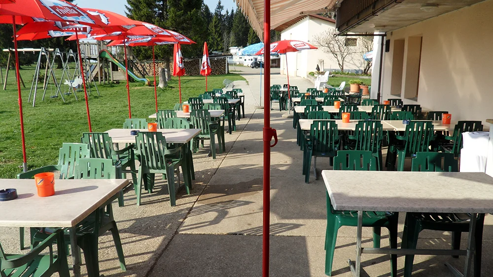 La terrasse du Café-Restaurant Les Cluds, avec ses tables et ses parasols.